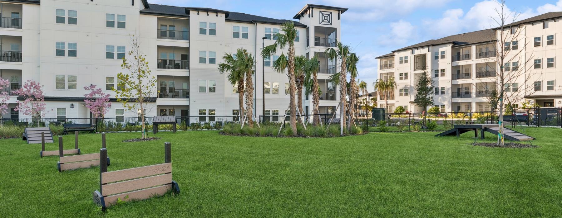 a dog park with a green lawn and a building in the background