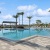 a pool with palm trees and building in the background