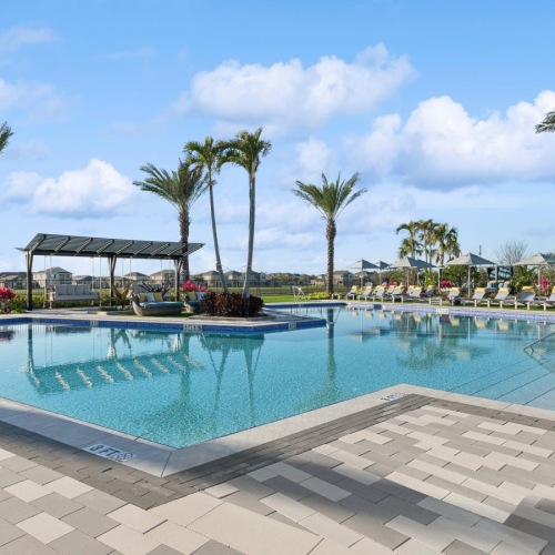 Shimmering resort-style pool a pool with palm trees and building in the background