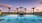 a pool with palm trees and a sunset